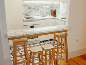 A kitchen with a marble countertop, wooden stools, and a patterned floor. - Apartment  by Interhome (Porto)