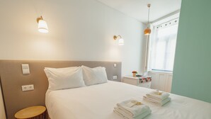 A hotel room with a bed, bedside tables, a small round table, and a window with curtains. - Apartment  by Interhome (Porto)