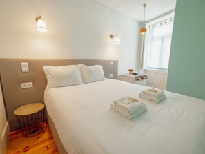 A hotel room with a bed, bedside tables, a small round table, and a window with curtains. - Apartment  by Interhome (Porto)