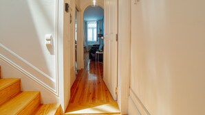 A hallway with wooden flooring, white walls, and a door leading to a room with a blue accent wall. - Apartment  by Interhome (Porto)