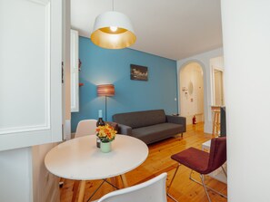 A modern living room with a grey sofa, a round white table with a vase of flowers, a floor lamp, and a painting on the wall. - Apartment  by Interhome (Porto)
