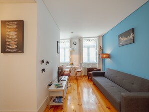 A modern living room with a grey sofa, wooden flooring, and a blue accent wall. - Apartment  by Interhome (Porto)