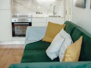 A green sofa with multiple cushions in a modern kitchen setting. - Apartment  by Interhome (Porto)