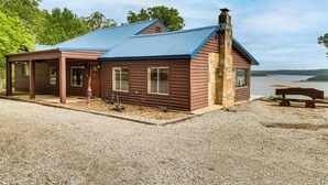 Een chalet met een metalen dak, houten bekleding en een stenen schoorsteen.