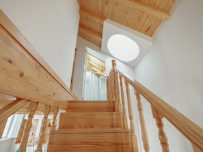 A wooden staircase with a handrail leading to a room with a large window and a circular skylight. - Apartment  by Interhome (Porto)