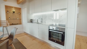 Una cucina moderna con mobili bianchi, forno integrato e microonde.