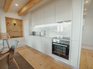 A modern kitchen with white cabinetry, a built-in oven, and a microwave. - Apartment  by Interhome (Porto)