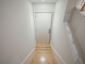 A narrow hallway with a wooden floor and white walls, leading to a closed door. - Apartment  by Interhome (Porto)