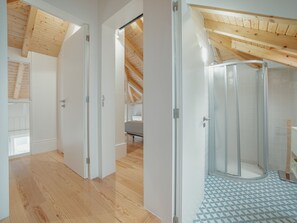 A modern interior with a wooden ceiling, a glass shower enclosure, and a patterned floor. - Apartment  by Interhome (Porto)