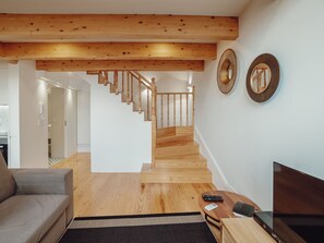 A modern living room with a wooden staircase, a sofa, a coffee table, and a TV. - Apartment  by Interhome (Porto)