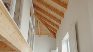 Un soffitto in legno con travi a vista, pareti bianche e una porta sulla destra.