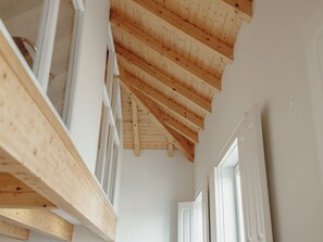 A wooden ceiling with exposed beams, white walls, and a door on the right. - Apartment  by Interhome (Porto)
