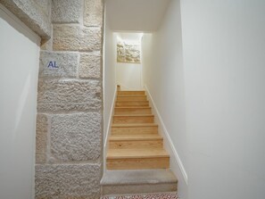 A staircase with stone walls and wooden steps leading to a landing. - Apartment  by Interhome (Porto)