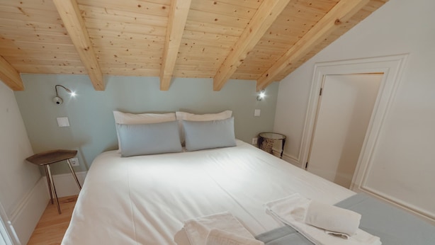 Una camera da letto con un letto grande, due lampade sui comodini, una sedia e una porta.