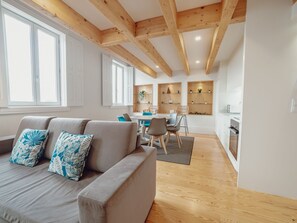 A modern living room with a sofa, dining area, kitchen, and wooden beams on the ceiling. - Apartment  by Interhome (Porto)