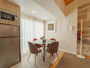 Eine moderne Küche mit Einbauofen, ein Essbereich mit rundem Tisch und Stühlen sowie eine Wand aus Stein.
