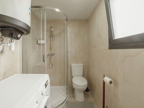 Ein Badezimmer mit Dusche, Toilette und Waschmaschine.