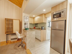 Eine moderne Küche mit Holzausstattung, einem Edelstahlkühlschrank, einer Mikrowelle und einem Barhocker.