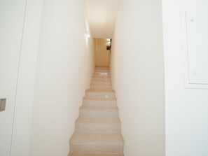 A narrow, well-lit stairway leading to a landing with a light switch on the wall. - Apartment  by Interhome (Porto)