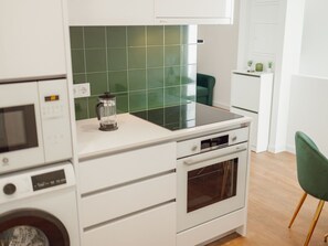 Une cuisine moderne équipée d’un four encastré, d’un four à micro-ondes et d’une machine à café posée sur le plan de travail.