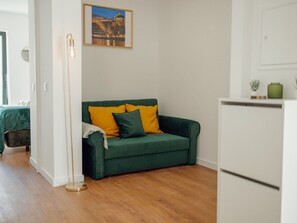 Ein Zimmer mit einem grünen Sofa, einem Bild an der Wand und einem weißen Kühlschrank.