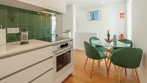 Et moderne køkken med et indbygget komfur, kaffemaskine og en backsplash i grønne fliser.