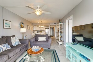 Ein Wohnzimmer mit einer Couch, einem Couchtisch, einem Fernseher und einem Deckenventilator.