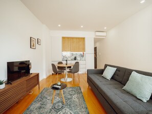 En moderne stue med sofa, fjernsyn og spiseplads med stole og bord.