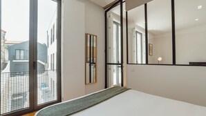 A modern bedroom with a large bed, a sliding glass door to the outside, and a large mirror on the wall. - Apartment  by Interhome (Porto)