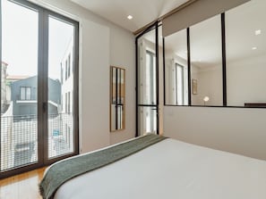 A modern bedroom with a large bed, a sliding glass door to the outside, and a large mirror on the wall. - Apartment  by Interhome (Porto)