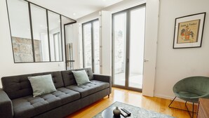 A modern living room with a grey sofa, a small round table, and a green chair. - Apartment  by Interhome (Porto)
