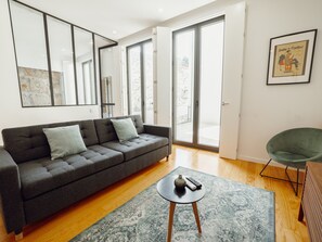 A modern living room with a grey sofa, a small round table, and a green chair. - Apartment  by Interhome (Porto)