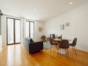 En moderne stue med sofa, spisebord, stole og et fjernsyn.