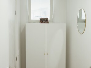 A white wardrobe with a radio on top, a mirror on the wall, and a window above. - Apartment  by Interhome (Porto)
