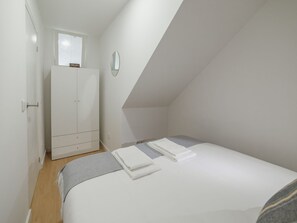 A bedroom with a bed, a wardrobe, a mirror, and a window. - Apartment  by Interhome (Porto)