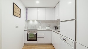 Eine moderne Küche mit weißen Schränken, einem eingebauten Backofen, einem Edelstahlkühlschrank und einer Marmor-Spritzschutzwand.