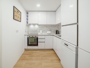 Eine moderne Küche mit weißen Schränken, einem eingebauten Backofen, einem Edelstahlkühlschrank und einer Marmor-Spritzschutzwand.