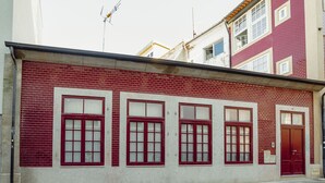 Ein Gebäude mit roter Ziegel Fassade, zahlreichen Fenstern mit weißen Rahmen und einer roten Tür.