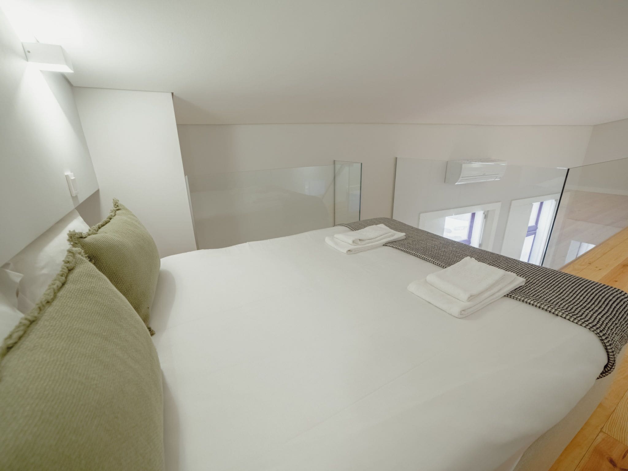 A hotel room with a large bed, a bedside table, a mirror, and a window.