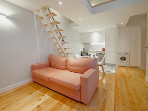 A modern living space with a wooden staircase, a sofa, a dining area, and a kitchen. - Apartment  by Interhome (Porto)