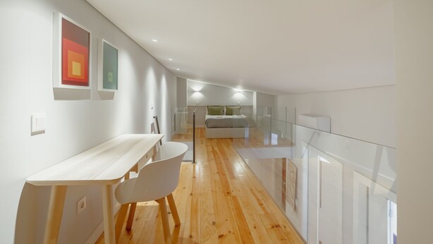 Ein modernes Interieur mit Holzdielen, einem weißen Schreibtisch und einem Glasgeländer.