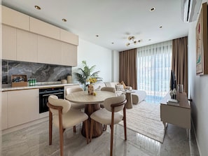 Ein modernes Wohnzimmer mit rundem Tisch, Sofas und einer Küchenzeile mit Marmorarbeitsplatte.