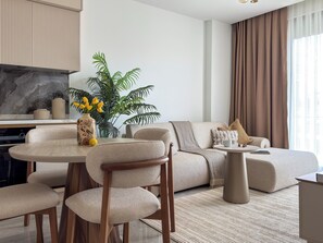 Ein modernes Wohnzimmer mit einer Couch, einem runden Couchtisch und einem Essbereich mit Stühlen.