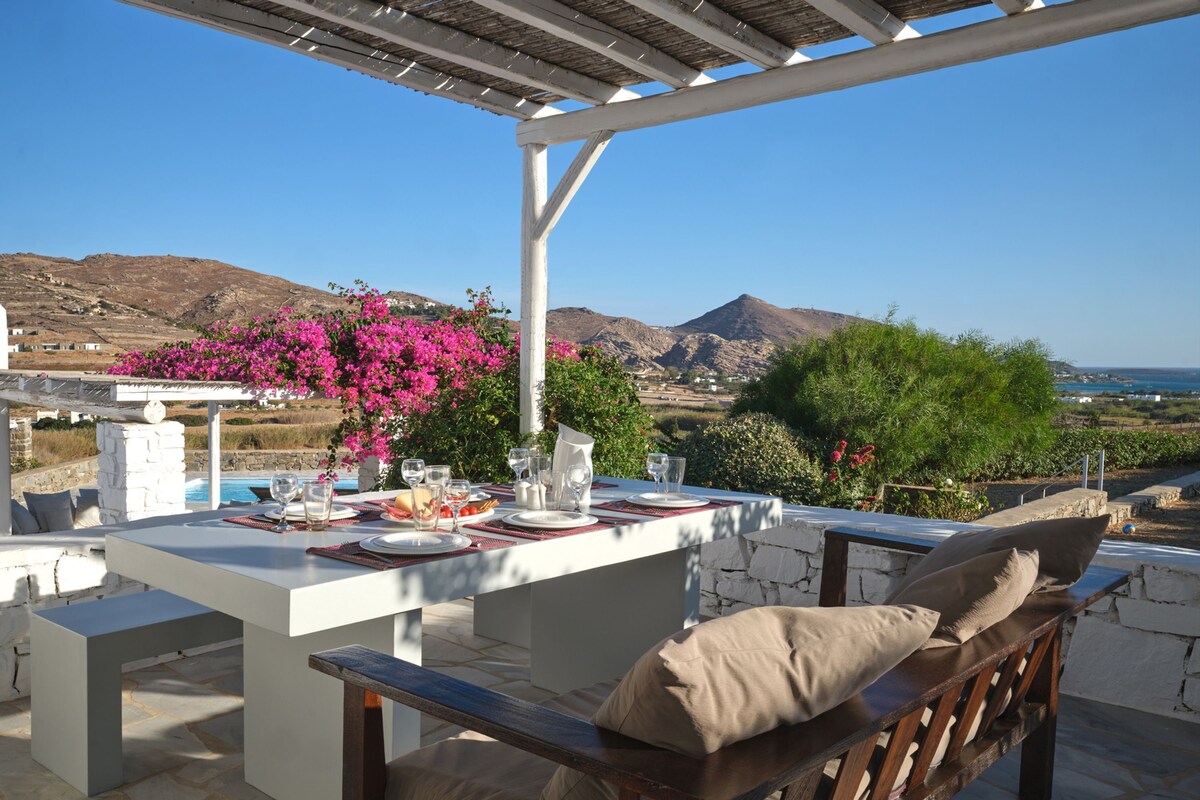 An outdoor dining area with a view of mountains and a pool.