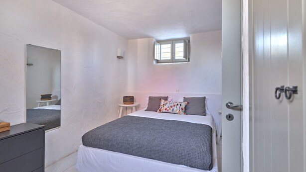 Ein Schlafzimmer mit einem Bett, einem Schminktisch, einem kleinen Tisch, einem Spiegel und einer Tür.