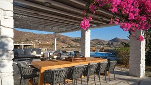 Eine Terrasse im Freien mit einem Holztisch und -stühlen, einem Pool und Blick auf die umliegende Landschaft.