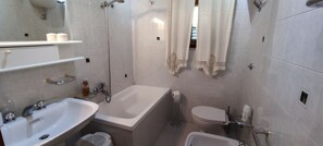 Ein Badezimmer mit einer Badewanne, einem Waschbecken, einer Toilette und einer Dusche.
