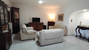 Una sala de estar con sofá, sillón, televisor y una mesa con objetos decorativos.