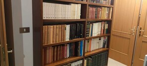Ein Bücherregal voller Bücher, eine Holztür und ein Lichtschalter an der Wand.