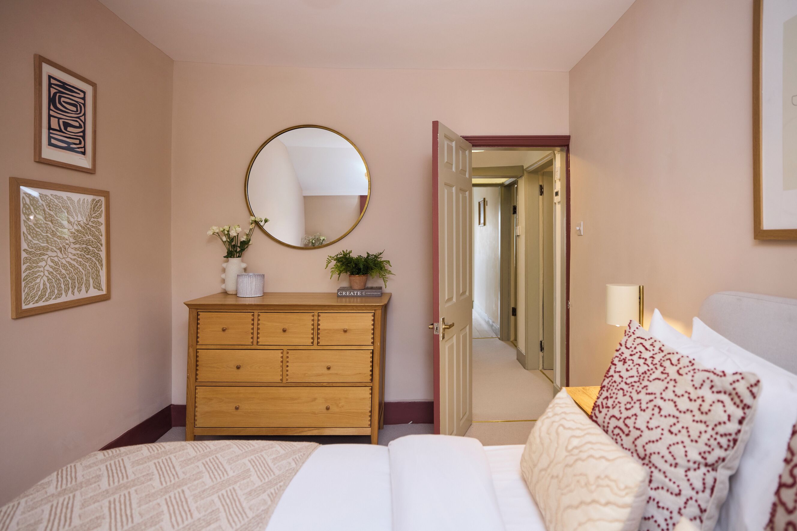 A bedroom with a bed, a dresser, a mirror, and a door leading to a hallway.